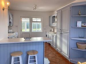 a kitchen with blue and white cabinets and stools at Cottage 465 - Cashel in Carna