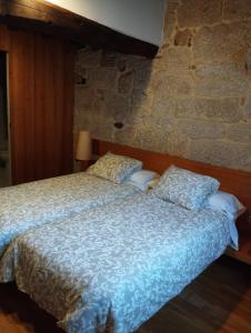 een bed in een kamer met een stenen muur bij Pensión rural Pallabarro in Allariz