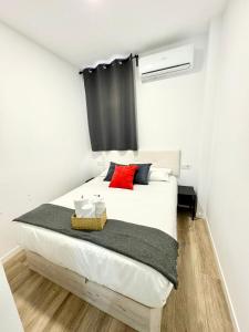 1 dormitorio con cama blanca y almohada roja en Apartamentos Madrid Connection - Universidad by Oshun Apartments, en Madrid