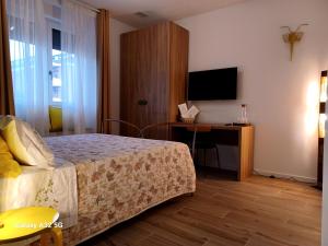 - une chambre avec un lit et un bureau avec une télévision dans l'établissement L'angolo di Luna, à Gorizia