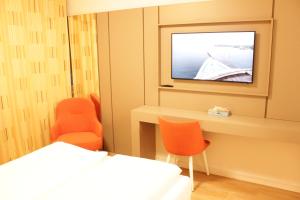 een kamer met een bed en twee stoelen en een televisie bij Isar City Hotel in München