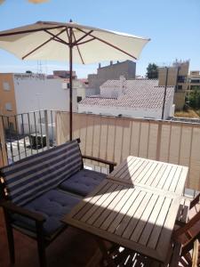a table and an umbrella and a bench on a balcony at Kione Vidalmar in Alcossebre