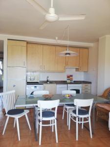 a kitchen with a table and some chairs and a table and cabinets at Kione Vidalmar in Alcossebre