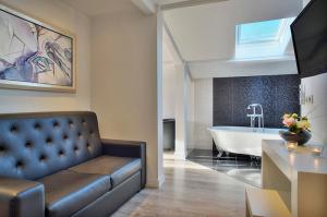 - un salon avec un canapé et une baignoire dans l'établissement Les Criquets Hôtel & Spa, à Blanquefort