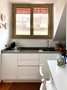 kuchnia z białymi szafkami i umywalką oraz 2 oknami w obiekcie Casa Ginepro via Mazzini w Turynie
