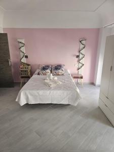 - une chambre avec un grand lit et un mur rose dans l'établissement Pompeya Merida suite, à Mérida
