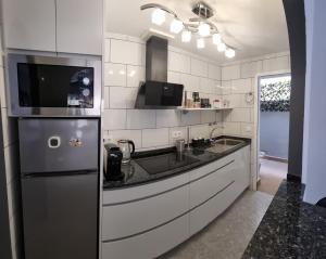 een keuken met een wastafel en een koelkast bij AYAHAY, Modern luxury apartment just 50 m from Playa Del Puerto in Puerto de Mazarrón