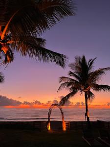 una palmera y un arco en la playa al atardecer en Pousada Quintal Caraíva, en Caraíva