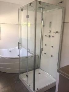 La salle de bains est pourvue d'une douche en verre et d'une baignoire. dans l'établissement Hermosa casa Minimalista en Solanas Vacation, à Punta del Este