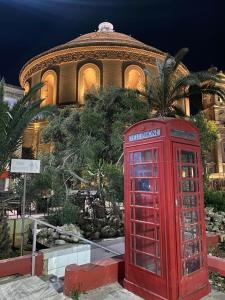 a red phone booth sitting in front of a building at Spacious room, king size bed, balcony, mirrors and luxury lights. in Mosta