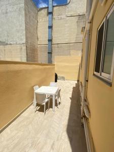 a patio with a white table and chairs on a building at Spacious room, king size bed, balcony, mirrors and luxury lights. in Mosta
