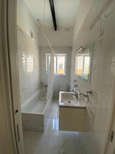 a white bathroom with a tub and a sink at Spacious room, king size bed, balcony, mirrors and luxury lights. in Mosta