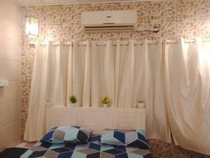 a room with white curtains and a bed with a fan at Ground floor bungalow in Mumbai