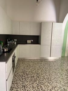 a kitchen with white cabinets and a patterned floor at Spacious room, king size bed, balcony, mirrors and luxury lights. in Mosta