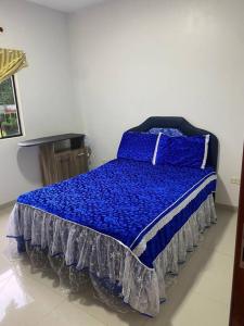 a bed with a blue comforter in a room at Apartamento, Salto del Guaira in Salto del Guairá
