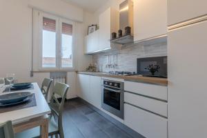 a kitchen with white cabinets and a table with chairs at Ferrara Il Castello Dazzling Apartment in Ferrara