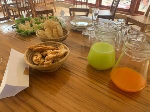 a wooden table with two baskets of food and orange juice at Hotal Khuruu Khuruu in Pajo