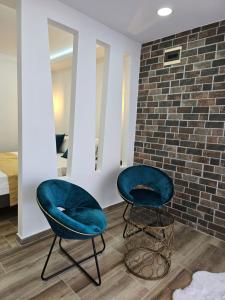 2 chaises bleues assises à côté d'un mur de briques dans l'établissement Apartments Mediteran, à Ulcinj