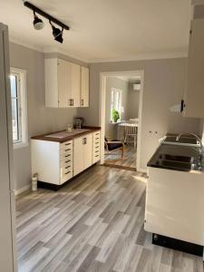 a kitchen with white cabinets and a wooden floor at A nice little cottage in Henån in Henån