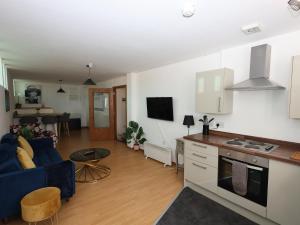 a living room with a blue couch and a kitchen at Stunning 2 Bed Apartment in Converted Church in Blackpool