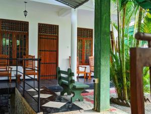 a green bench sitting on the porch of a house at Golden Pearl Safari Villa in Udawalawe