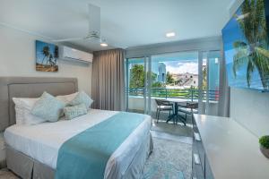 a bedroom with a bed and a balcony with a table at Blue Haven Holiday Apartments in Christ Church
