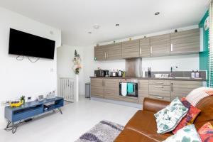 ein Wohnzimmer mit einem Sofa und einer Küche in der Unterkunft Wakefield City Centre - Parking, Self Check-in, Wi-Fi, Workspace, Balcony - Families, Contractors, Long Stays - Alt-Stay in Wakefield