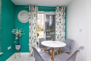 uma sala de jantar com paredes verdes e uma mesa e cadeiras brancas em Wakefield Centre - Off Road Parking, Self Check-in, Fast Wi-Fi, Balcony - Families, Contractors, Long Stays em Wakefield