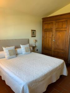 a bedroom with a white bed with a wooden cabinet at B&B I Ligustri in Lucca