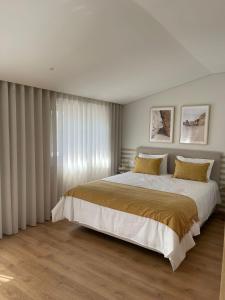 OPORTO Suites في Moreira: غرفة نوم بسرير كبير مع مخدات صفراء