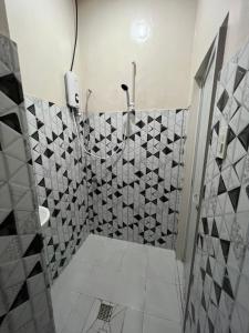 a bathroom with a shower with a tiled wall at Nelli’s Place in Allauan