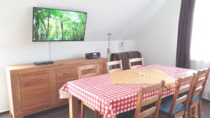 a dining room with a table and a tv on a wall at FeWo Quint nahe Kap Arkona in Altenkirchen