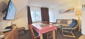 sala de estar con mesa, TV y sofá en FeWo Quint nahe Kap Arkona, en Altenkirchen