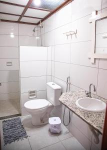La salle de bains blanche est pourvue de toilettes et d'un lavabo. dans l'établissement Pousada das Gaivotas, à Guaibim