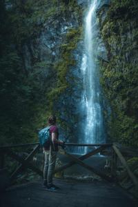 a man standing on a bridge in front of a waterfall at Glamping Lumbre in Salento