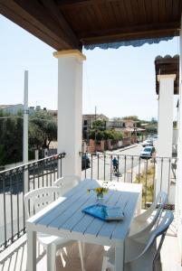 un tavolo blu e sedie bianche sul balcone di Porto Frailis 2 a Tortolì