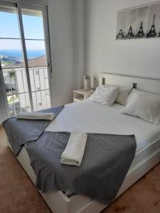 a white bedroom with a large bed with a large window at Small Oasis Nelson Mandela Apartment with sea view, two bedrooms, parking, terrace and pool in Manilva