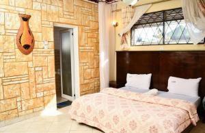 1 dormitorio con cama y pared de piedra en Country lake resort Garuga, en Wakiso