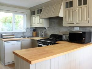 a kitchen with white cabinets and a wooden counter top at Sandpipers in Ventnor +96 photos
