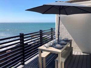 a table with an umbrella on a balcony with the ocean at Sandpipers in Ventnor