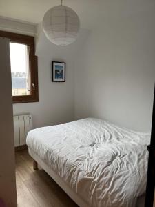 een wit bed in een slaapkamer met een raam bij Renovated apartment - near the beach in Ouistreham