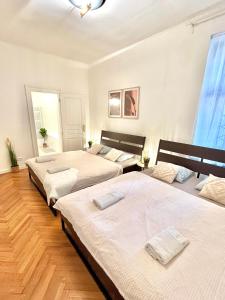 Apartment Mia - Old Town في براتيسلافا: ثلاثة أسرة في غرفة نوم بجدران بيضاء وأرضية خشبية