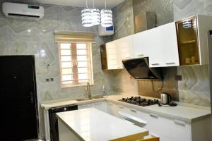 uma cozinha com armários brancos, um fogão e uma janela em FAMVILLE em Ikuata