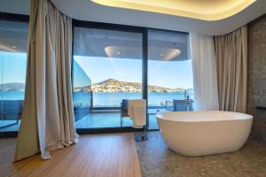 baño con bañera frente a una ventana grande en ALYACHT Premium Hotel, en Sarandë