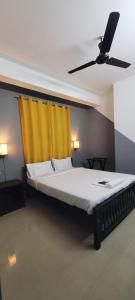 a bedroom with a bed with a yellow curtain at Tulip Homes by The Oaks Inn in Cochin