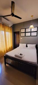 a bedroom with a large bed with a ceiling fan at Tulip Homes by The Oaks Inn in Cochin