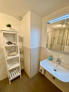 uma casa de banho com um lavatório branco e um espelho. em Ferienwohnung „Zuckerbäckerei“ em Kitzingen
