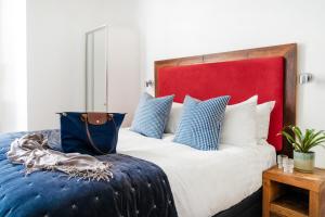a bed with blue and white pillows and a red headboard at Berkeley Suites in Bristol