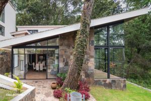 una casa in pietra con porte in vetro e un albero di Cabaña de lujo en La Toscana Mazamitla 1 a Mazamitla