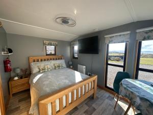 a bedroom with a bed and a large window at Duirinish Pods with Private Hot Tubs and Duirinish Bothy with No Hot Tub in Plockton